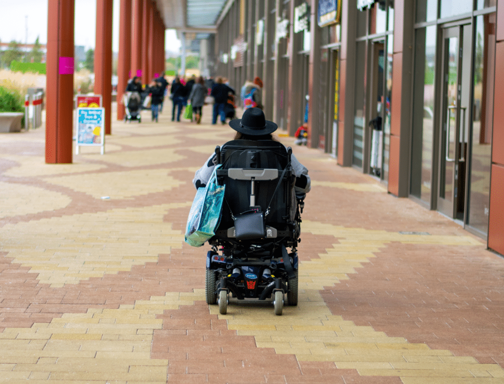 Image: Back of a wheelchair, with store fronts to the right.