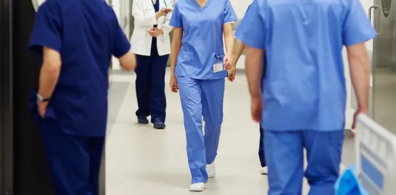 IMAGE - Nurses in blue walking in a white corridor